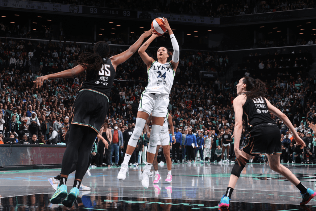 A basketball court with a WNBA logo in the center, surrounded by players in action, conveying the excitement and energy of the WNBA season.